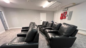A room with a black leather sectional sofa, a white door, and a red fire extinguisher on the wall. - 7BR w/ Heated Pool Jacuzzi, Theatre (Pompano Beach)