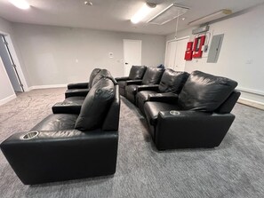 A room with a black leather sectional sofa, a white door, and a red fire extinguisher on the wall. - 7BR w/ Heated Pool Jacuzzi, Theatre (Pompano Beach)