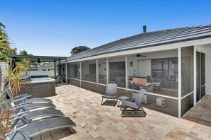 A covered outdoor area with lounge chairs, a hot tub, and a patio with a view of the building's interior. - 7BR w/ Heated Pool Jacuzzi, Theatre (Pompano Beach)