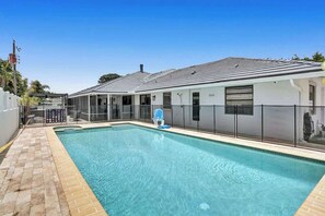 A rectangular swimming pool with a tiled deck, a covered seating area, and a fenced patio. - 7BR w/ Heated Pool Jacuzzi, Theatre (Pompano Beach)