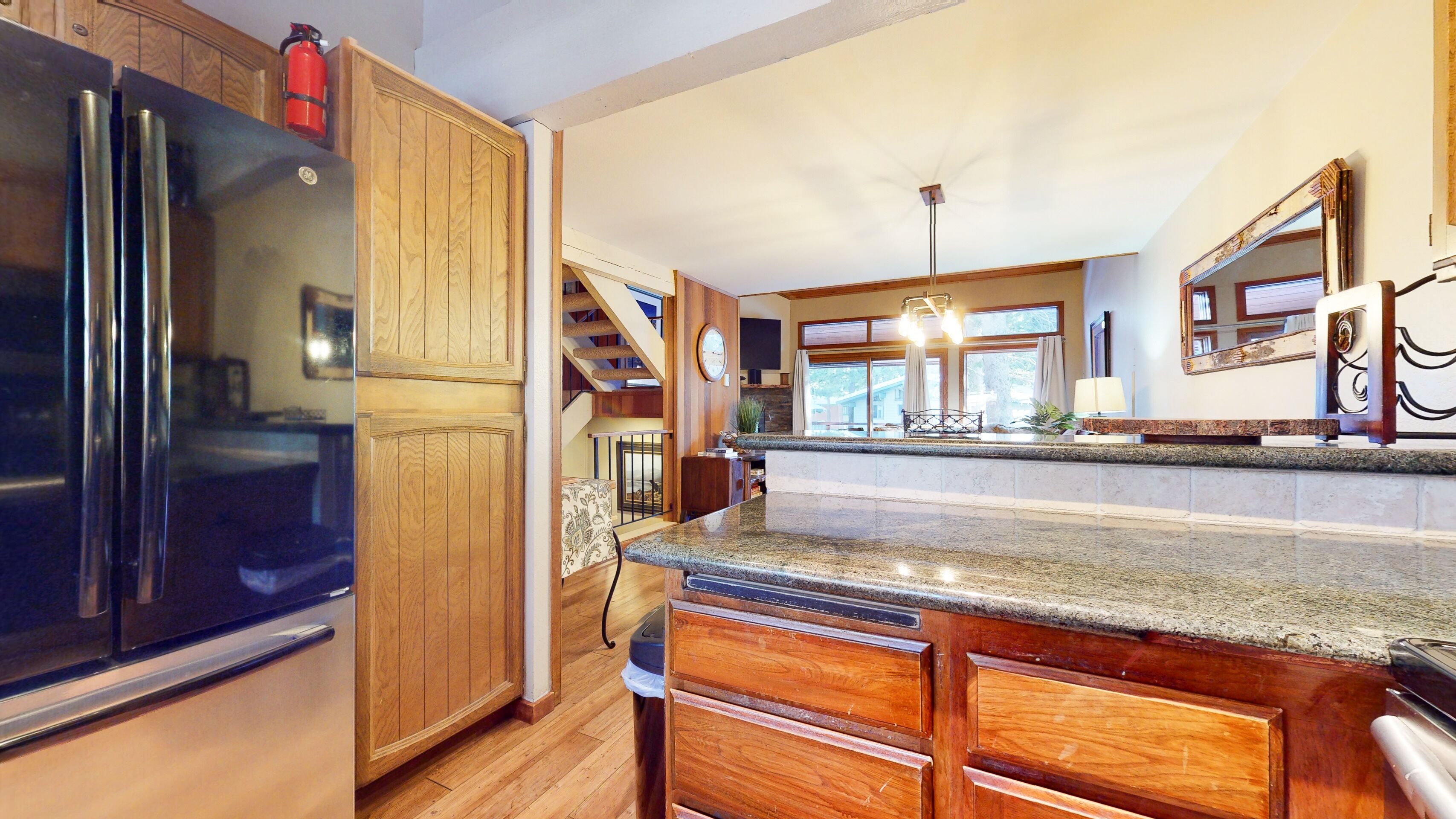 A kitchen with wooden cabinets, a stainless steel refrigerator, granite countertops, and a built-in stove.