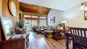 A cozy living room with a wooden ceiling, a large window, a sofa, a coffee table, and a chair. - Modern Large Home, Quiet Location, Near Winter Shuttle, Ice Rink & Bowling (Mammoth Lakes)