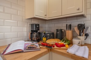 A kitchen with white cabinets, a coffee maker, a toaster, and various cooking utensils.