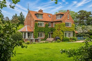 A large brick house with a sloped roof, multiple windows, and a well-maintained garden. - Holmbush, Thornham, Norfolk (Thornham)