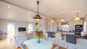 Una cocina moderna con armarios blancos, una isla central e iluminación colgante.
