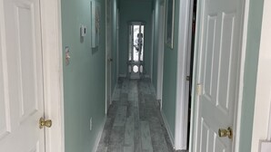 A hallway with white doors, a light green wall, and a wooden floor. - Beach Block Beauty with Ocean Views (Wildwood)