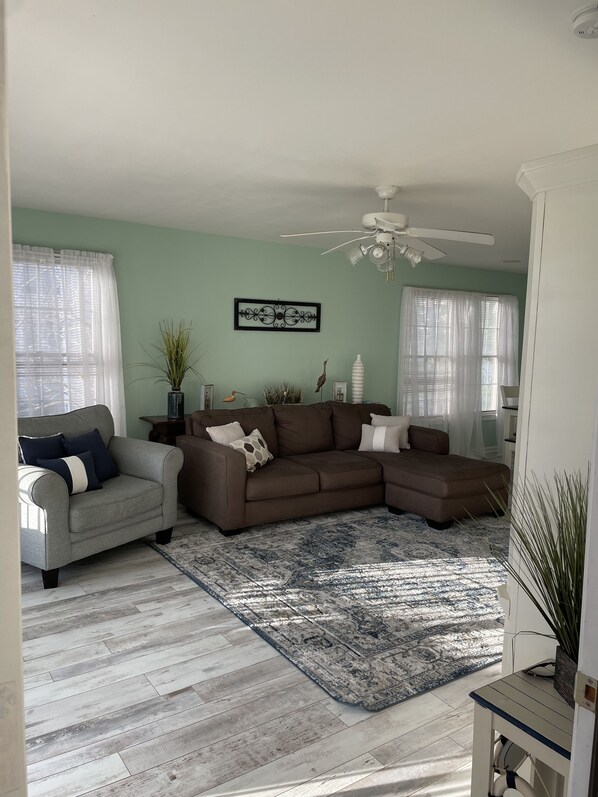 A living room with a grey sofa, a white armchair, and a blue patterned rug.