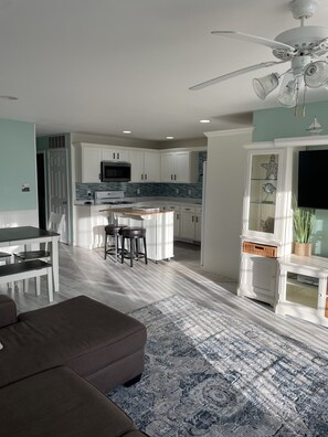 A modern kitchen with white cabinets, a central island, and a ceiling fan.
