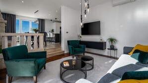 A modern living room with a sofa, armchairs, and a coffee table. There is a flat-screen TV mounted on the wall and a staircase leading to an upper level. - Villa Moreta with heated pool, Sauna, Hot-tub (Okrug Gornji)