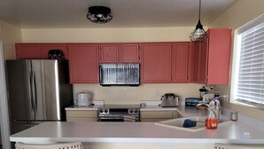 A kitchen with a central island, two bar stools, a refrigerator, a stove, and a window with blinds. - 3BR 2.5 baths in this Quiet and Safe Community NW of Tucson Arizona. (Tucson)