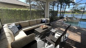 Eine sonnendurchflutete Terrasse mit einer Couch, Korbstühlen und einem kleinen Tisch.