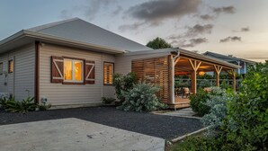 Una casa moderna con un porche cubierto y un jardín cuidado.