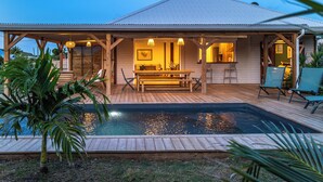 Una casa con piscina, terraza de madera y zona de estar al aire libre.