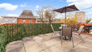 An outdoor patio with a table and chairs, a large umbrella, and a brick building in the background. - Apartment in the hear of the city, live like a local (Oxford)