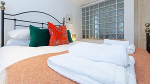 A neatly made bed with white and green pillows, a folded white towel, and an orange textured blanket. - Apartment in the hear of the city, live like a local (Oxford)