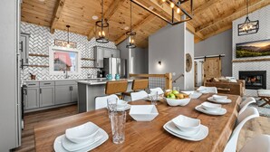 A modern kitchen with a herringbone-patterned backsplash, wooden ceiling beams, and pendant lighting. - New Modern Mountain Retreat with Spectacular Views (Sevierville)