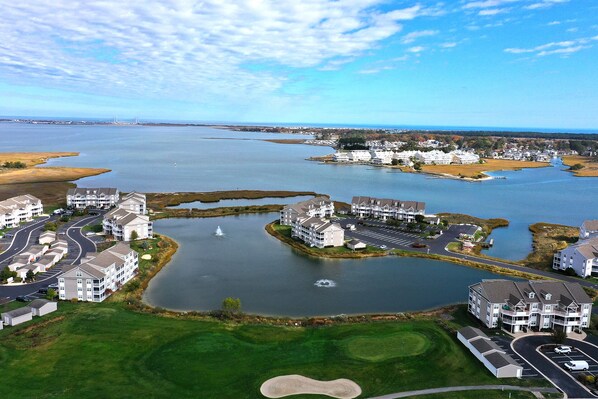 An aerial view of a coastal residential area with multiple apartment buildings, a golf course, and a marina.