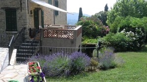 Ein Steinhaus mit einem Balkon, ein Garten mit Lavendel und ein weißes Markisen
