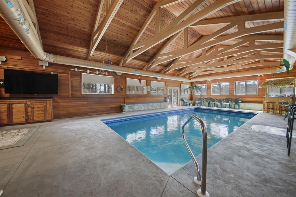 Une piscine intérieure avec un plafond en bois et un téléviseur sur le côté gauche.