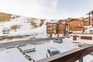 A snow-covered street with a building featuring wooden balconies and a ski lift visible in the background. - 200m from ski slopes, 3rd floor, view mountain, balcony, parking, tv, 26m², La Plagne (La Plagne)