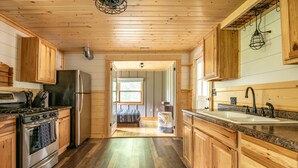 Eine Küche mit Holzwänden, einem Edelstahlherd, einem Kühlschrank und einer Arbeitsplatte aus Granit.