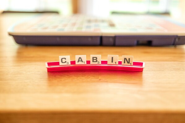 Wooden blocks spelling "CABIN" on a table with a laptop in the background.