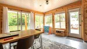 Ein Holzinterieur mit Esstisch, Stühlen und einem Babybett.