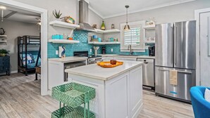A modern kitchen with a central island, stainless steel appliances, and a blue backsplash.