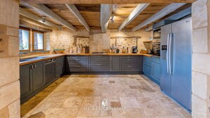 A kitchen with dark cabinets, a blue refrigerator, and a stone wall backsplash. - Dezie Manor Grange and Gardens near Sarlat la Caneda (Val de Louyre et Caudeau)