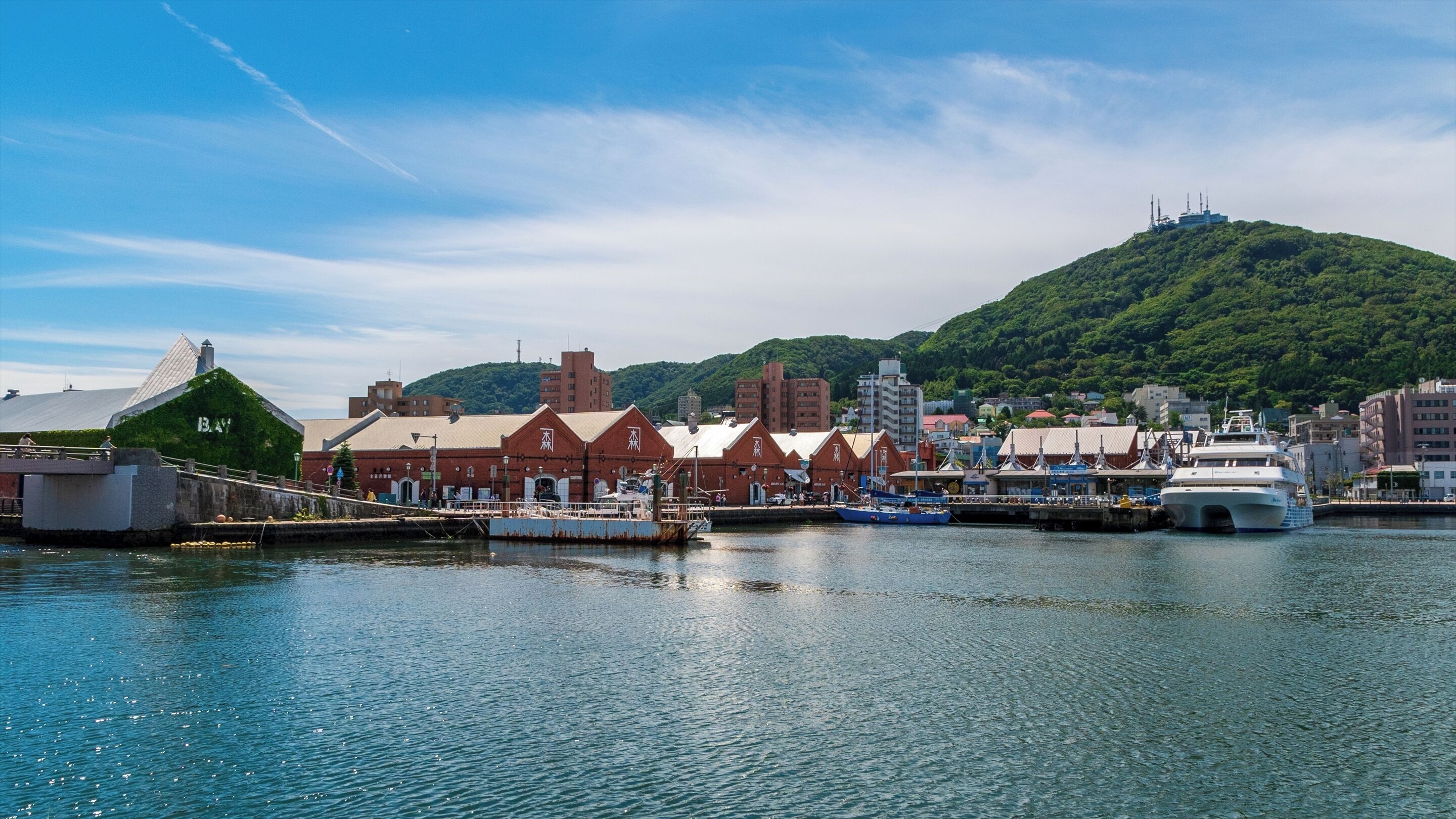 A waterfront with a dock, boats, and buildings with traditional architecture.