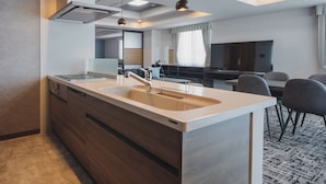 A modern kitchen with a large island, built-in appliances, and a dining area with a TV and seating. - Gran Palette Hakodate (Hakodate)