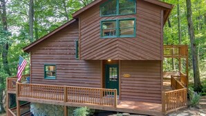 A wooden cabin with a green door, a balcony, and an American flag.