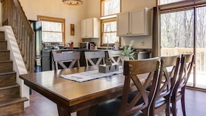 A spacious kitchen with wooden cabinets, a dining table with chairs, and a staircase leading to another level.