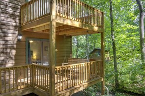 A two-story wooden deck with a glass door and a hanging swing chair. - Brookhaven - Tranquil Maggie Valley Cabin with Deck & Fire Pit! (Maggie Valley)