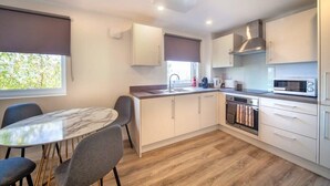 A modern kitchen with white cabinets, a marble-top dining table, and a built-in oven. - 2BR Apartment near Ashford Town | Balcony & WiFi (Ashford)