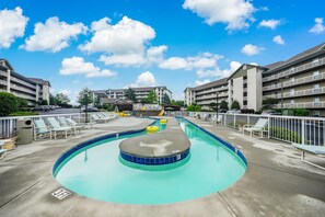A swimming pool with a water slide, lounge chairs, and a clear blue sky. - Whispering Pines 124 by Jackson Mountain Rentals (Pigeon Forge)