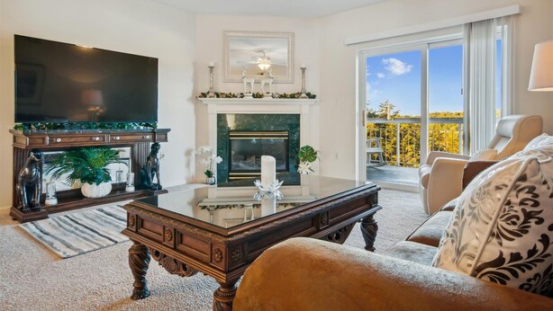 A living room with a fireplace, a television, and a balcony with a view.
