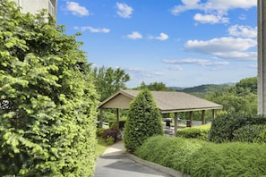 A gazebo with a clear view of the surrounding greenery and a pathway leading to it. - Whispering Pines 124 by Jackson Mountain Rentals (Pigeon Forge)