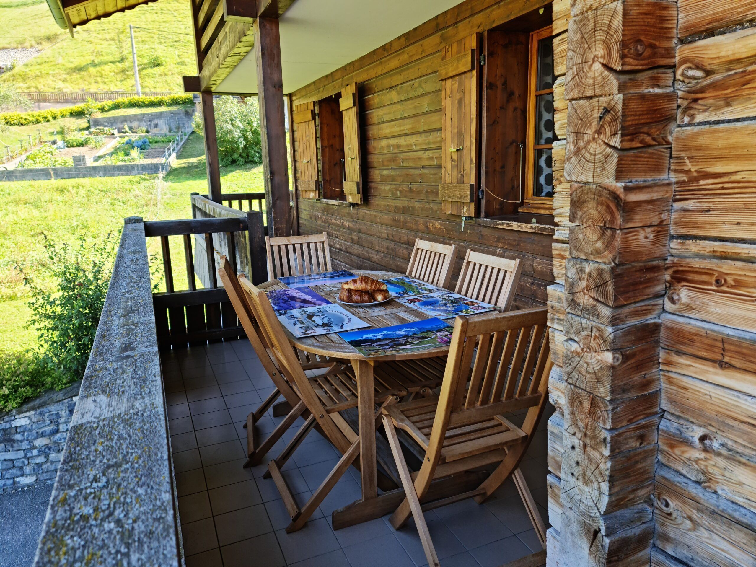 A wooden cabin with a dining table set for four, surrounded by wooden chairs.