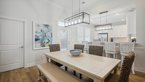 Un comedor con una gran mesa rectangular, bancos y una lámpara colgante.