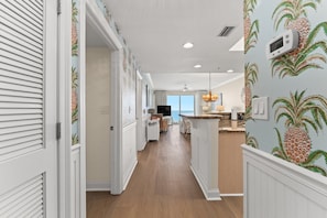 A kitchen with a central island, white cabinetry, and a pineapple-themed wall. - Brand new 2 bed + 2 bath Boardwalk retreat, perfect for small families. (Panama City Beach)