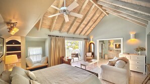 Une chambre spacieuse avec un grand lit, un ventilateur de plafond et une vue sur l’extérieur.