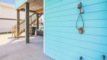A turquoise building exterior with a metal door knocker and a staircase leading to an upper level.