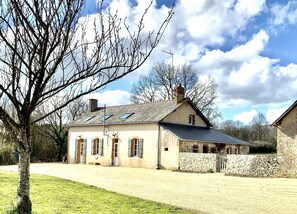 A two-story stone building with a sloped roof, multiple windows, and a stone wall. - Welcome to the Farm (Bécon-les-Granits)