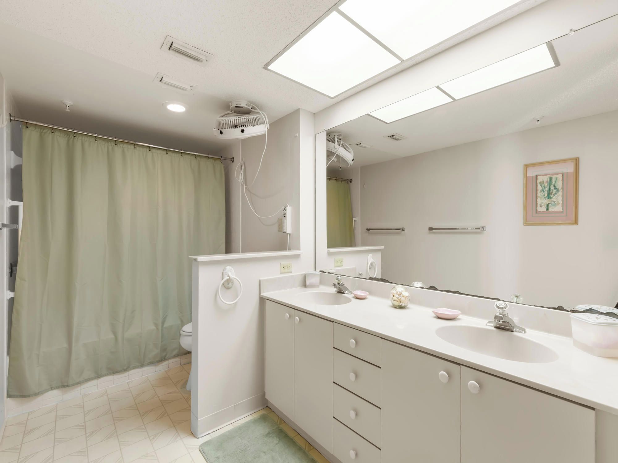 Un baño moderno con un espejo grande, dos lavamanos, una ducha y un inodoro.