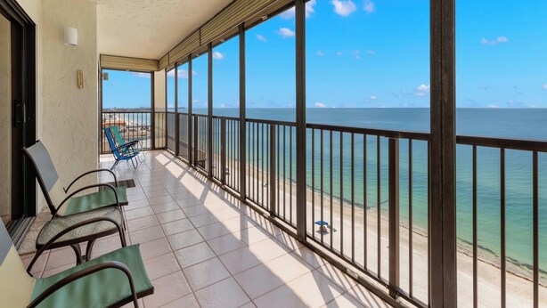 A balcony with a view of the sea, featuring a tiled floor and metal railings. - Ocean Sands 1101 by Distinctive Beach Rentals (Madeira Beach)
