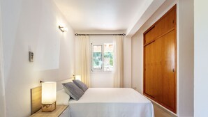 A bedroom with a bed, bedside table, lamp, curtains, and a view of the outdoors. - VILLA CAS PUIG Two houses in 1 !!!!  with 2 full kitchen, air conditioned in all the rooms! (Sant Joan de Labritja / San Juan)