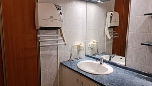 Un baño moderno con encimera de mármol, un lavabo, un espejo y un secador de pelo fijado a la pared.
