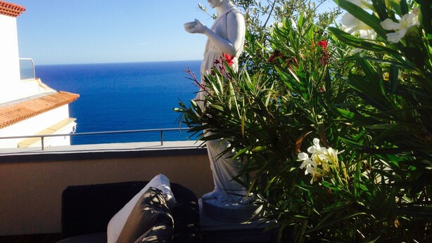 Une statue sur un balcon donnant sur l’océan.
