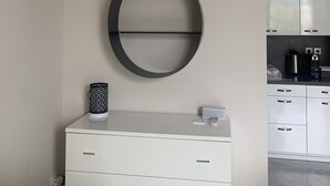 Une cuisine moderne avec des meubles blancs, une machine à café noire et blanche, et une étagère murale originale.